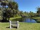 Park bench overlooking a serene pond with a fountain, surrounded by lush greenery and clear blue sky at 107 Jose Gaspar Dr, Englewood, FL 34223