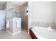 A modern bathroom with a glass shower, soaking tub, and neutral tile at 12605 Bacchus Rd, Port Charlotte, FL 33981