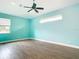 A spacious bedroom with a ceiling fan, bright teal walls, and wood-look tile at 12605 Bacchus Rd, Port Charlotte, FL 33981