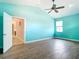 A spacious bedroom with a ceiling fan, bright teal walls, and wood-look tile at 12605 Bacchus Rd, Port Charlotte, FL 33981