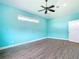A spacious bedroom with a ceiling fan, bright teal walls, and wood-look tile at 12605 Bacchus Rd, Port Charlotte, FL 33981