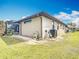 Exterior side view of home featuring screened in patio, lawn, and outdoor HVAC at 12605 Bacchus Rd, Port Charlotte, FL 33981
