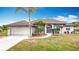 Charming single-story home with a manicured lawn, a two-car garage, and lush landscaping at 12605 Bacchus Rd, Port Charlotte, FL 33981