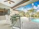 Covered patio with ceiling fan, tile flooring, rocking chairs and screened-in pool with spa at 12605 Bacchus Rd, Port Charlotte, FL 33981