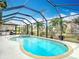 Backyard swimming pool and spa under a screened lanai with tropical landscaping at 12605 Bacchus Rd, Port Charlotte, FL 33981
