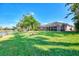 Spacious backyard featuring well-manicured lawn, mature trees and a view of the screened in patio at 14236 Silver Lakes Cir, Port Charlotte, FL 33953