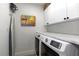 Functional laundry room boasts white cabinets, a tiled backsplash, and modern appliances for efficient cleaning at 14236 Silver Lakes Cir, Port Charlotte, FL 33953