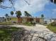 Exterior view of a yellow single-story home with boarded windows and a sandy yard with palm trees at 1432 Lemon Bay Dr, Englewood, FL 34223