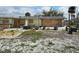 Rear view of a weathered single-story home featuring plywood-covered windows and overgrown vegetation at 1432 Lemon Bay Dr, Englewood, FL 34223