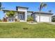 Charming one-story home featuring an attractive front yard with lush green grass and palm trees at 15498 Seafoam Cir, Port Charlotte, FL 33981