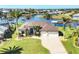 Charming single-Gathering home featuring a manicured lawn, mature landscaping, and a paved driveway leading to a two-car garage at 15690 Viscount Cir, Port Charlotte, FL 33981