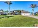 Beautifully landscaped front yard with mature palm trees and a well-maintained lawn leading up to a spacious two-car garage at 15690 Viscount Cir, Port Charlotte, FL 33981