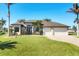 Beautiful home with a well-manicured lawn, mature palm trees, and a convenient two-car garage, offering great curb appeal at 15690 Viscount Cir, Port Charlotte, FL 33981