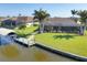Home includes screened in lanai, lush lawn, mature palms, and dock at 15690 Viscount Cir, Port Charlotte, FL 33981