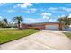 Charming coral home featuring a two-car garage, lush lawn, solar panels, and tropical landscaping at 1694 Harbor W Cir, Largo, FL 33770