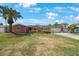 Charming coral home featuring a two-car garage, lush lawn, solar panels, and tropical landscaping at 1694 Harbor W Cir, Largo, FL 33770