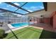 In-ground pool in screened enclosure features artificial turf and brick outdoor kitchen at 1694 Harbor W Cir, Largo, FL 33770