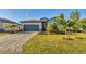 Charming single-story home with gray paint, a well-manicured lawn, and a paver driveway at 1824 Saddlewood Cir, Port Charlotte, FL 33953