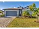 Charming single-story home with gray paint, a well-manicured lawn, and a paver driveway at 1824 Saddlewood Cir, Port Charlotte, FL 33953