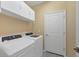 Convenient laundry room equipped with a washer, dryer, and overhead cabinets for ample storage at 1824 Saddlewood Cir, Port Charlotte, FL 33953