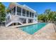 Backyard view of the rectangle pool featuring brick pavers and a covered porch on two levels at 19 Grouper Hole Dr, Boca Grande, FL 33921