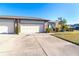 Home featuring a driveway, garage, stone facade, and well-maintained landscaping at 214 Aspen St # 51, Englewood, FL 34223