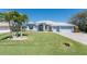 Charming single-story home with a well-manicured lawn, lush landscaping, and a light blue exterior at 228 White Marsh Ln, Rotonda West, FL 33947