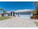 Exterior view of a light blue home with a three-car garage and brick-paved driveway at 228 White Marsh Ln, Rotonda West, FL 33947