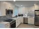 Modern kitchen with stainless steel appliances, white cabinets, and sleek backsplash at 2405 N Beach Rd # 10, Englewood, FL 34223
