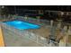 Illuminated community pool surrounded by lounge chairs and a safety fence at night at 2405 N Beach Rd # 10, Englewood, FL 34223
