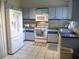 A view of the well-lit kitchen featuring white appliances, ample cabinet space, and a clean tile floor at 26191 Angelica Rd, Punta Gorda, FL 33955