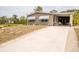 Tan home with a covered carport and awning-covered windows with long, freshly poured concrete driveway at 3021 Holly Ave, Englewood, FL 34224