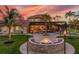 Beautiful backyard with a fire pit, palm trees, a covered patio, and an outdoor pool at sunset at 3700 Como St, Port Charlotte, FL 33948