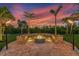 Inviting fire pit area with built-in seating, tiki torches, and a picturesque sunset backdrop at 3700 Como St, Port Charlotte, FL 33948
