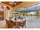 Outdoor dining with a wooden table, cushioned chairs, a ceiling fan and a screened in pool in the background at 3700 Como St, Port Charlotte, FL 33948