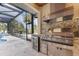 Luxury outdoor kitchen featuring a built-in grill, granite countertops, and a stainless steel beverage cooler, perfect for entertaining at 3700 Como St, Port Charlotte, FL 33948