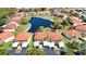 A beautiful aerial view of a community with a pond, lush trees, carports, and well-maintained landscaping at 405 Pine Hollow Cir # 405, Englewood, FL 34223