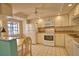 Well-lit kitchen featuring white appliances and cabinets, complemented by a tile floor and a bright window at 405 Pine Hollow Cir # 405, Englewood, FL 34223