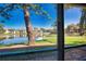 Screened patio view overlooking a serene lake, lush landscaping, and charming condominium buildings under a clear blue sky at 405 Pine Hollow Cir # 405, Englewood, FL 34223