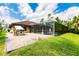 Green backyard with brick patio, a screened-in lanai featuring a pool, and house exterior at 4238 Golfair Ln, North Port, FL 34288