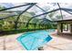 An expansive screened-in pool with an attached jacuzzi tub surrounded by lush greenery at 4238 Golfair Ln, North Port, FL 34288