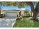 Charming single-story home with a red tile roof, well manicured lawn, landscaping, and a two car garage at 4308 Summertree Rd, Venice, FL 34293