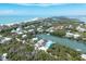 Aerial view of a coastal home with waterfront access surrounded by lush greenery and a sandy beach at 50 Tarpon Way, Placida, FL 33946