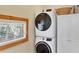 Bright laundry area features a stacked washer and dryer, window, and white storage cabinets at 50 Tarpon Way, Placida, FL 33946