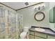 Bathroom with a shower/tub combination, a round mirror above the sink and neutral wall color at 6345 Bodmin Ln, North Port, FL 34291