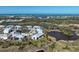 An aerial view shows the community with lush landscaping, a pond, and glimpses of the ocean at 6800 Placida Rd # 272, Englewood, FL 34224