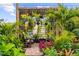 Inviting backyard patio with pergola, comfortable seating, hanging plants, and lush landscaping, creating a tranquil outdoor space at 7339 Thomas St, Englewood, FL 34224