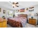 Bright bedroom featuring a ceiling fan, side tables, a bed with a colorful quilt, and a window with shutters at 7339 Thomas St, Englewood, FL 34224