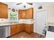 Galley kitchen featuring stainless steel appliances, a tile backsplash, wood cabinets, and a white door to the exterior at 7339 Thomas St, Englewood, FL 34224
