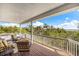 Covered balcony with comfortable seating offering a serene view of lush trees and the ocean in the distance at 9 Peekins Cove Dr, Boca Grande, FL 33921